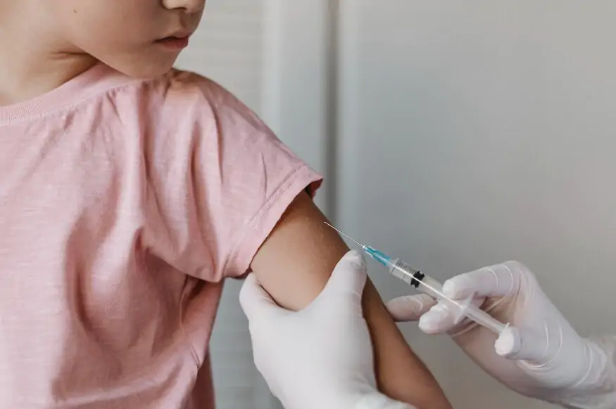 A healthcare worker administering a vaccine injection to a child's upper arm.